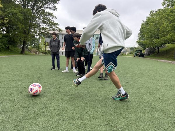 An 8th grader kicks a penalty shot while his peers witness