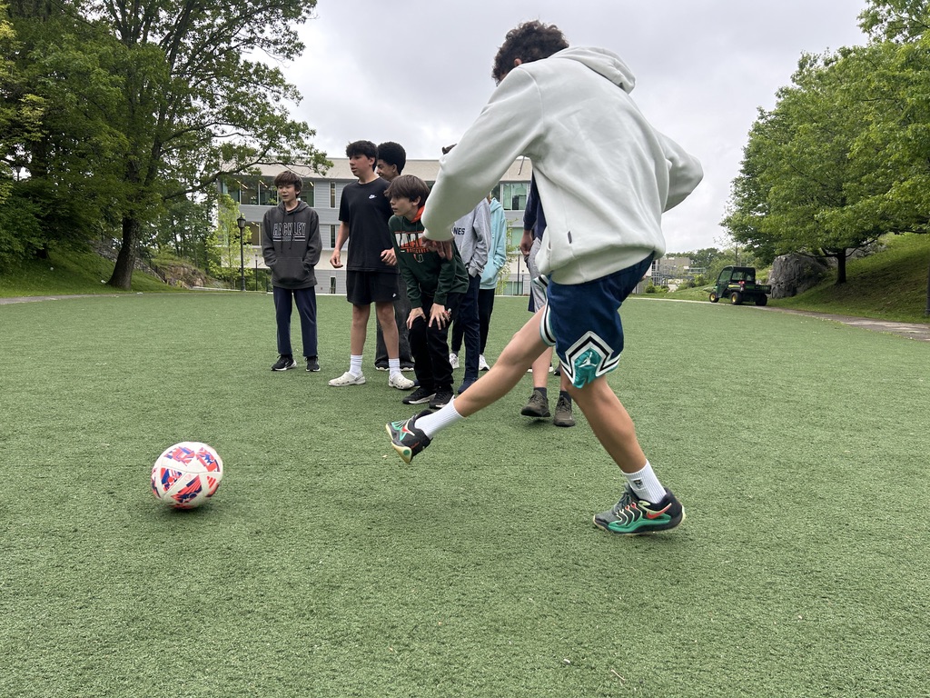 An 8th grader kicks a penalty shot while his peers witness